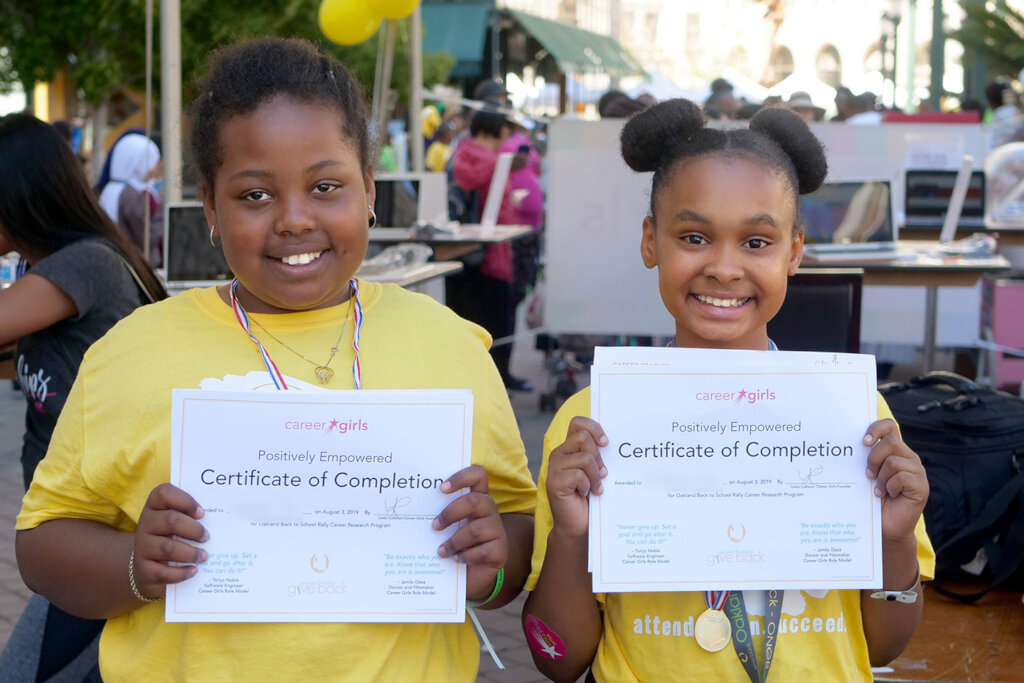 two girls proudly show their certificates