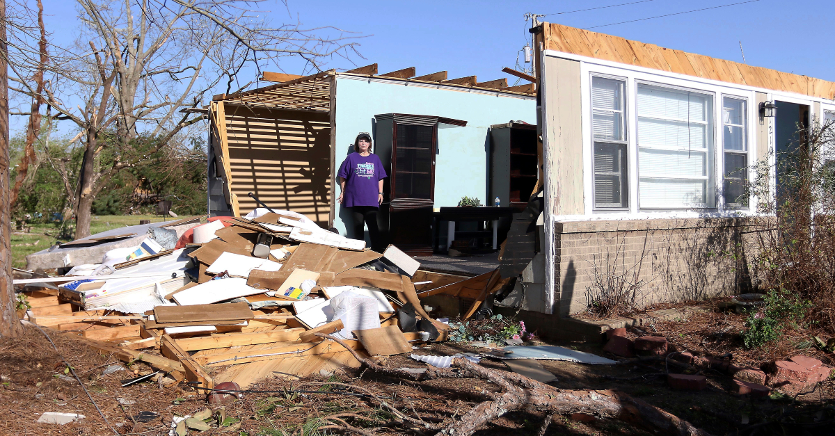 A woman stands in front of a home destroyed by a tornado northeast of Rolling Fork, Mississippi