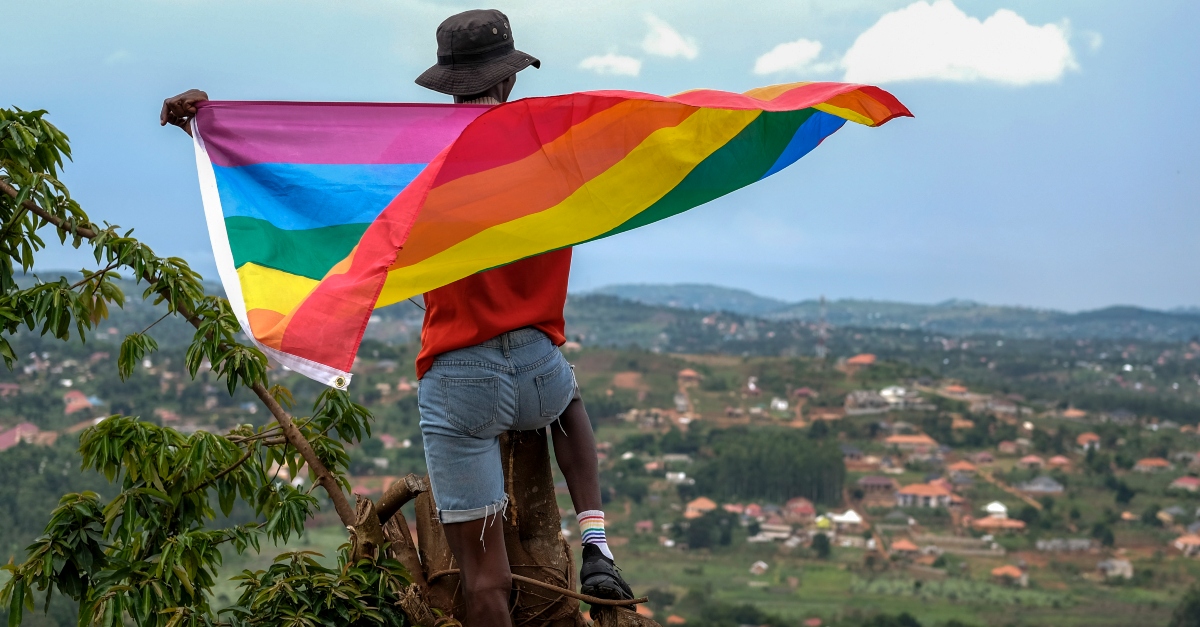A gay Ugandan man holds a pride flag as he poses for a photograph in Uganda Saturday, March 25, 2023. LQBTIQ+ Uganda