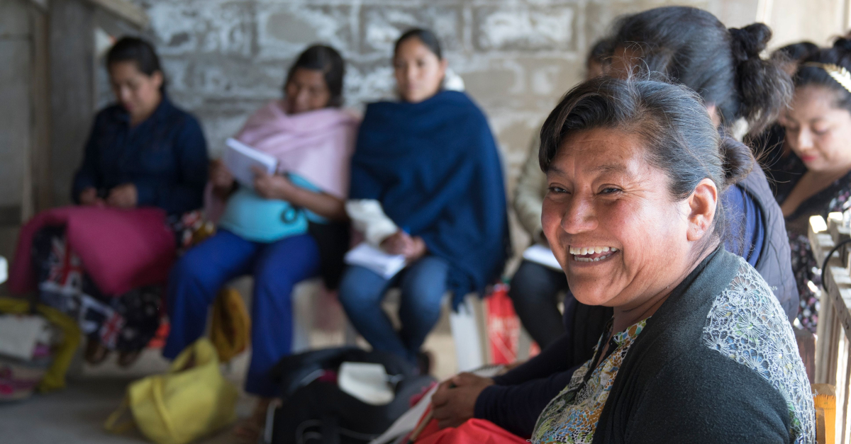 Woman in group of women looks at the camera, laughing.