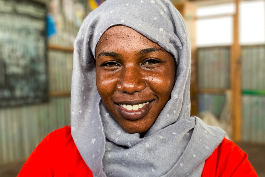 woman in grey hijab smiles at the camera refugee notes