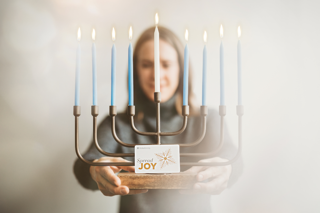 Woman holding menorah and GlobalGiving Gift Card for Hanukkah by Lisa Damico