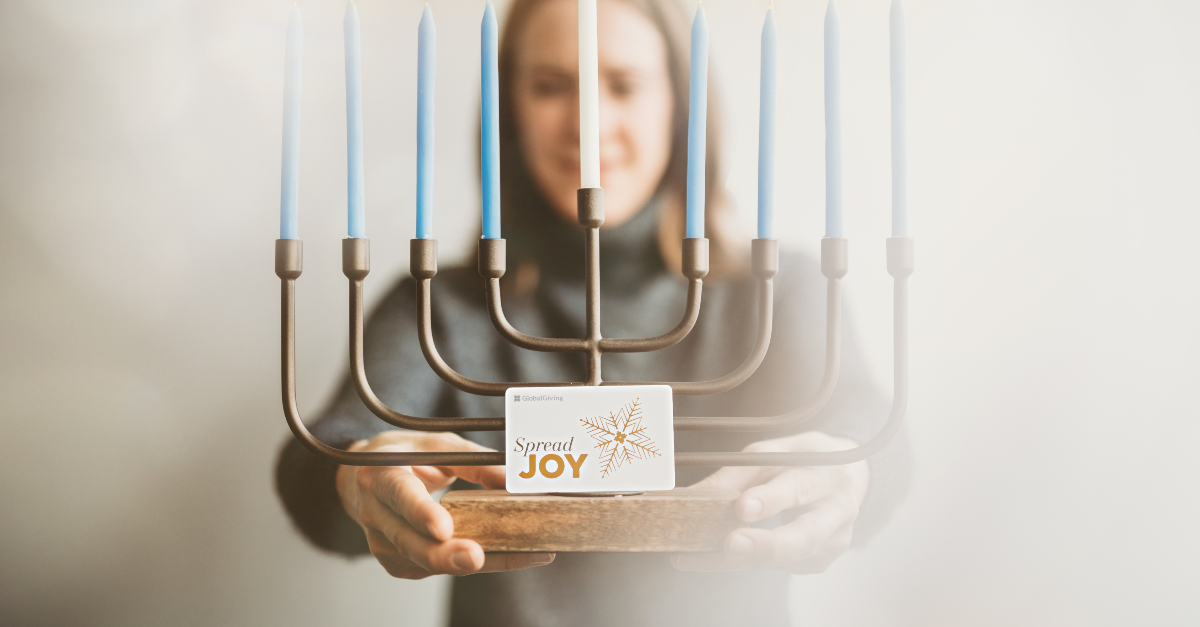 Woman holding menorah and GlobalGiving Gift Card for Hanukkah by Lisa Damico