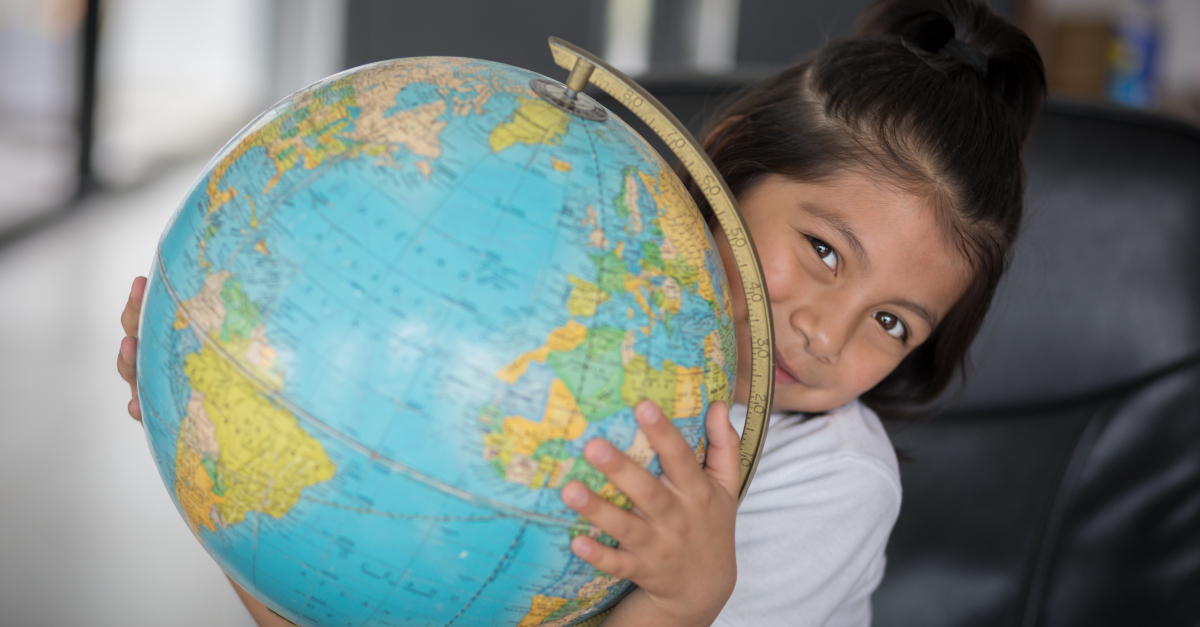 Girl smiling, holds world globe sustainable travel