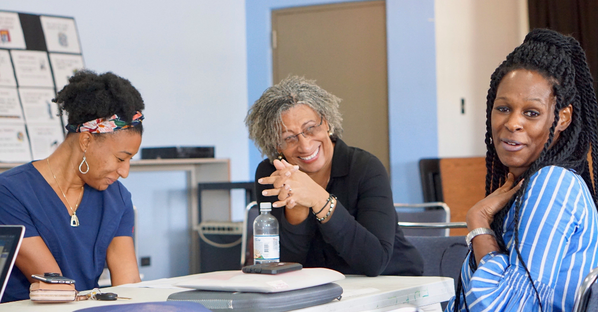 three women sit at meeting table, laughing corporate nonprofit partnership