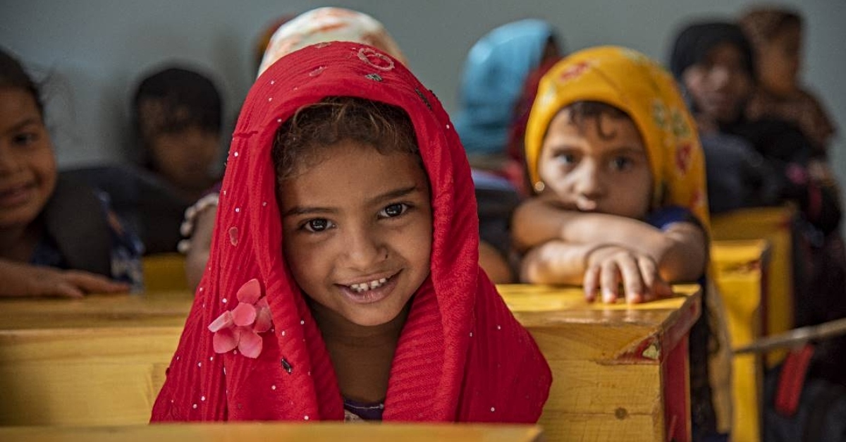 schoolgirl in classroom smiles at camera