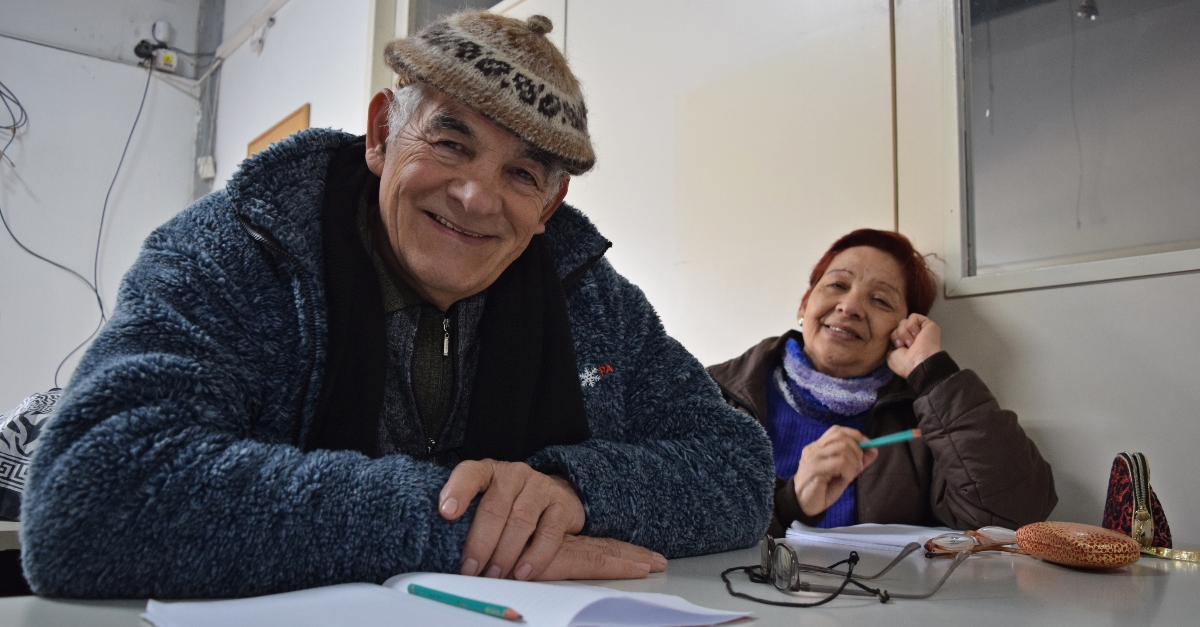 two seniors sit at a desk filling out paper, smiling