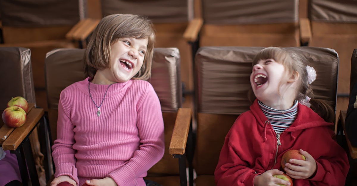 two young children sit next to each other laughing together givingtuesday campaigns