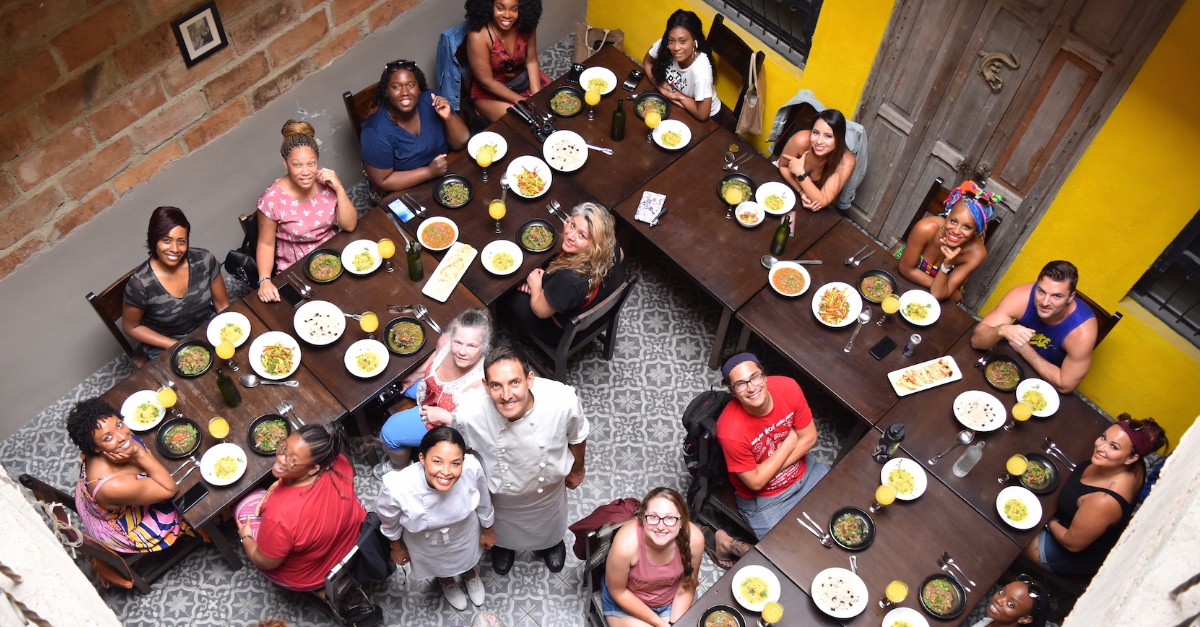 a group of people sit at tables in a circle and look up, smiling at the camera