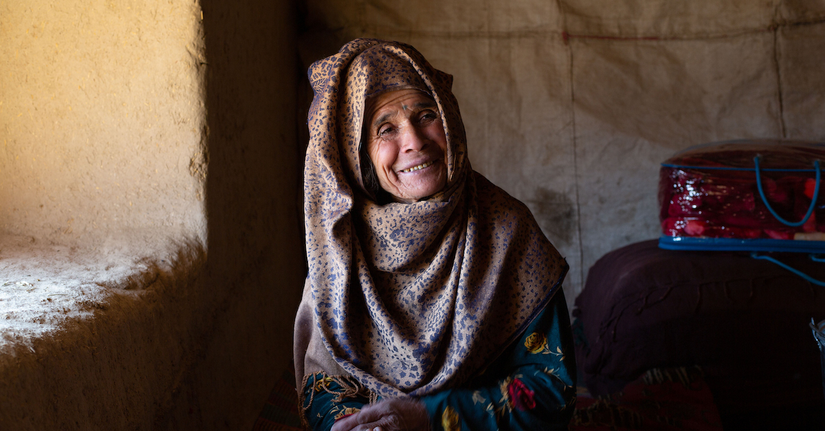 elderly woman sits next to window and smiles Afghanistan crisis
