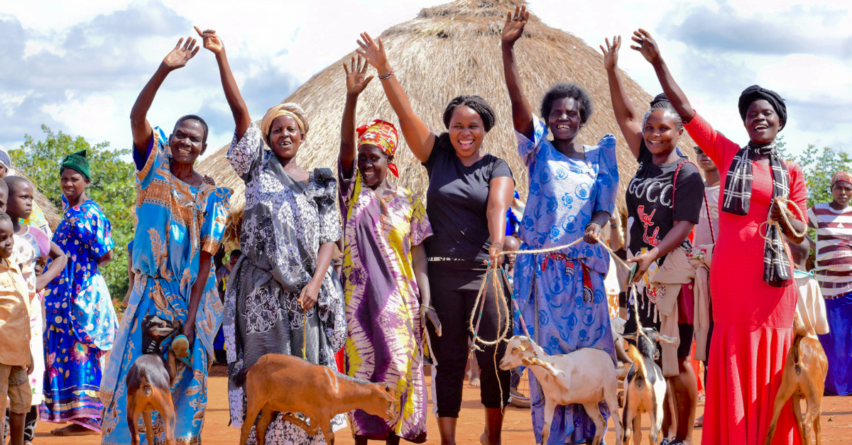 women smile at camera raising their hands high above their heads. Engage employees GivingTuesday