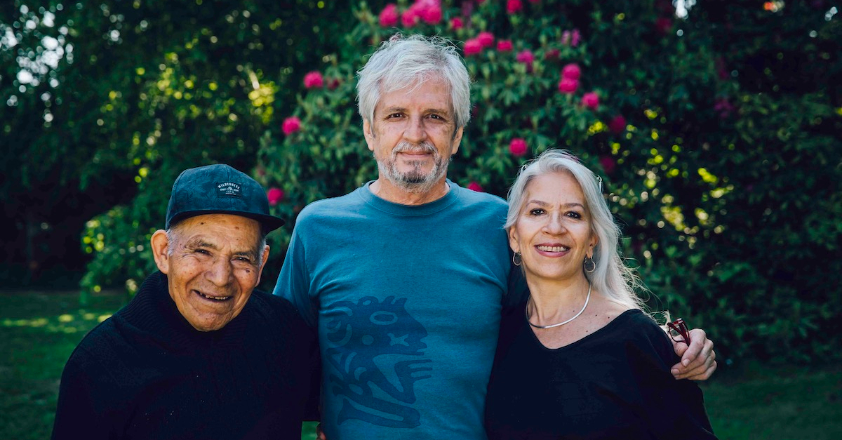 three grey-haired people stand together and smile