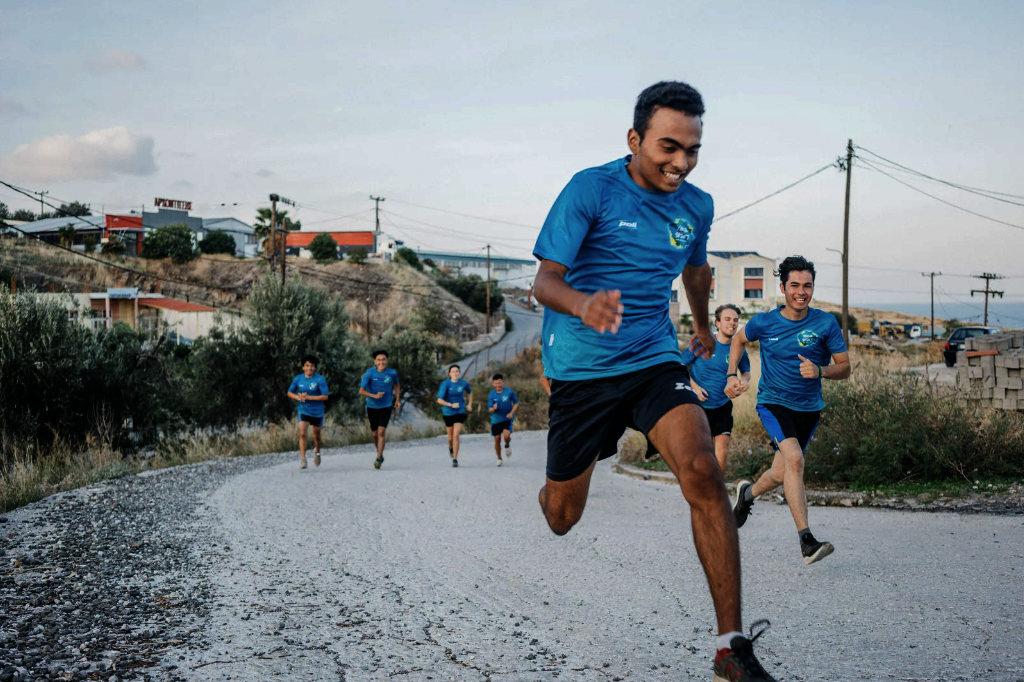 runners wearing matching shirts sprint down a road