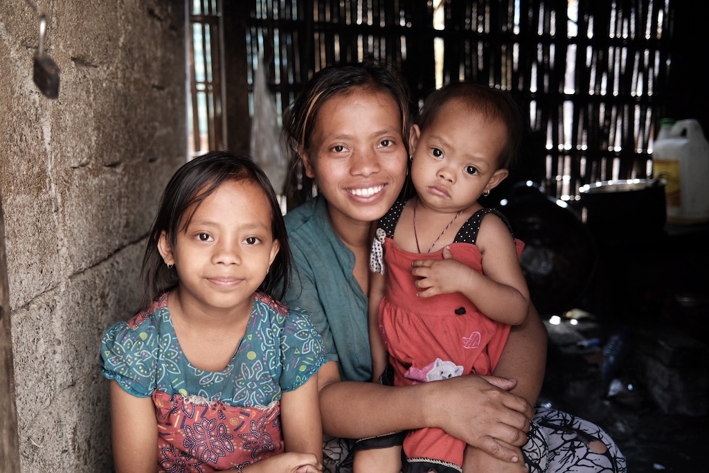 mother and her two young girls smile at the camera inspiring nonprofit photos of 2023