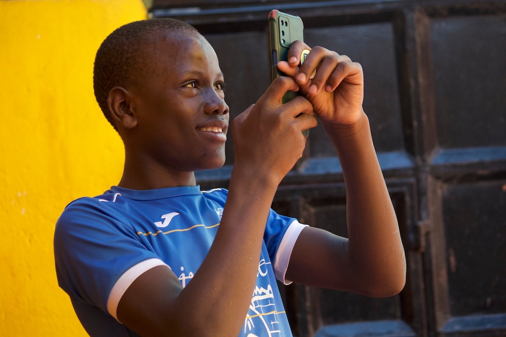 boy smiles as he looks at his phone