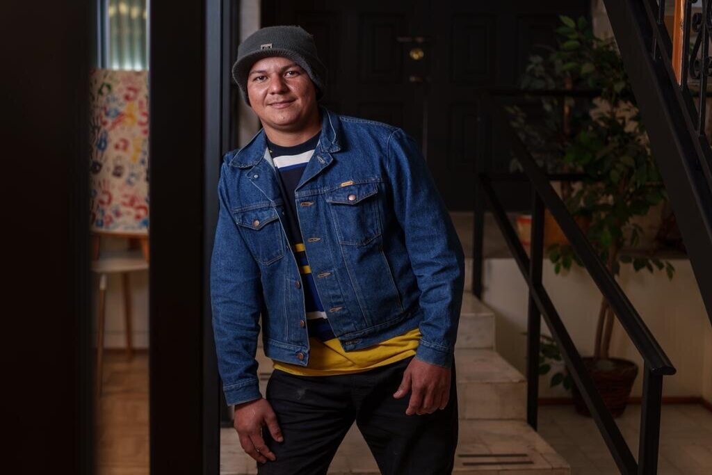 Ivan, an immigrant from Venezuela, leans on a door and smiles