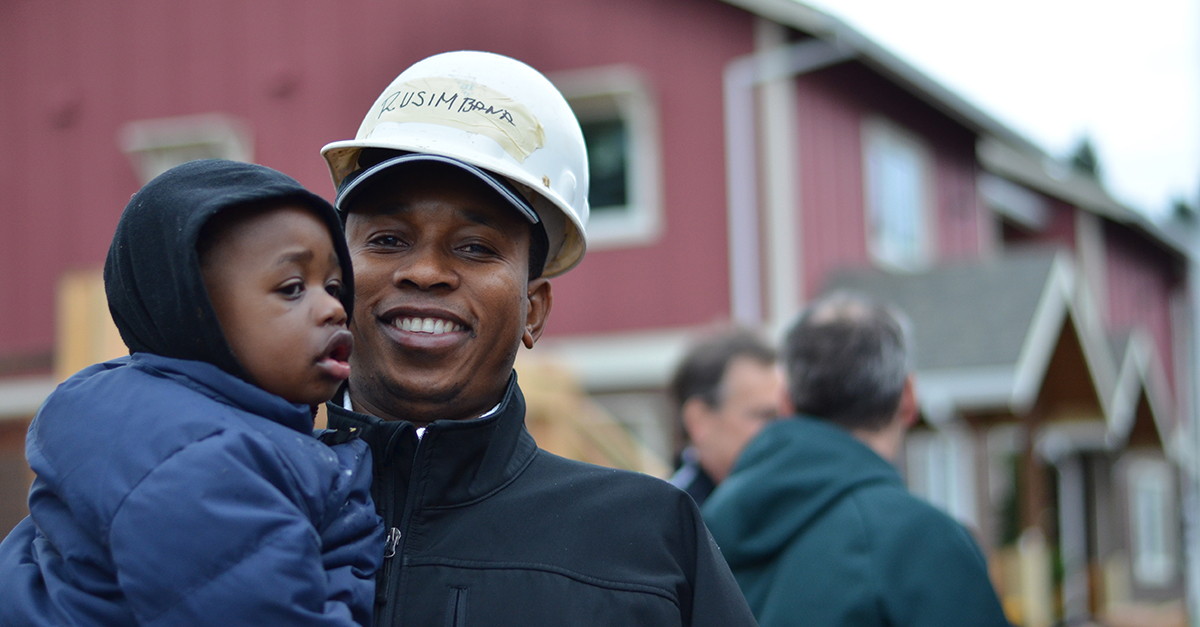 How to help the economy this election season. A man and child outside a home construction site by Habitat for Humanity Portland Metro East dba Habitat for Humanity Portland Region.