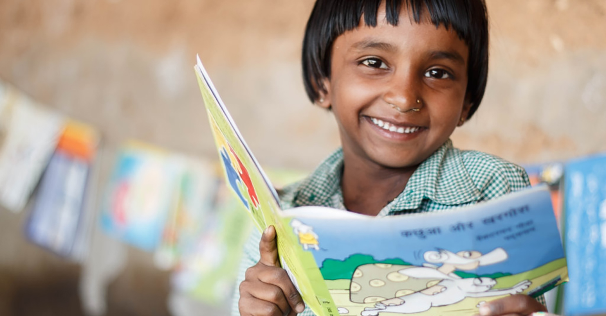 A little girl reads a book in India. Photo by Seva Mandir.