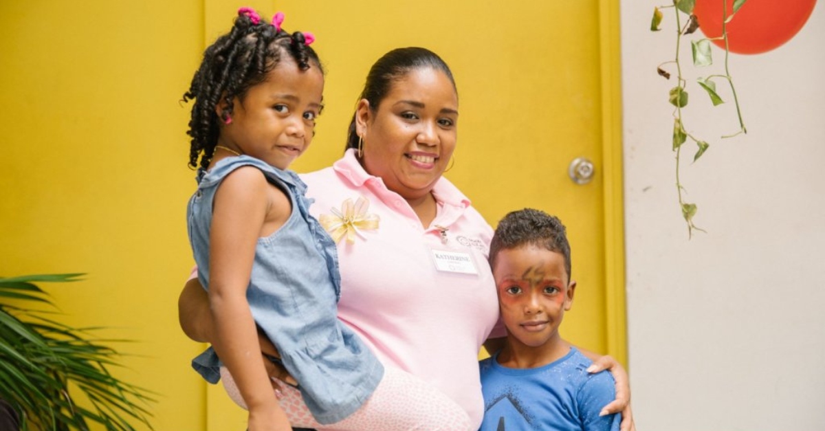 A family stands for a photo in front of a yellow door,