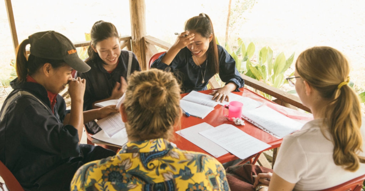 A team reviews documents at a table outside