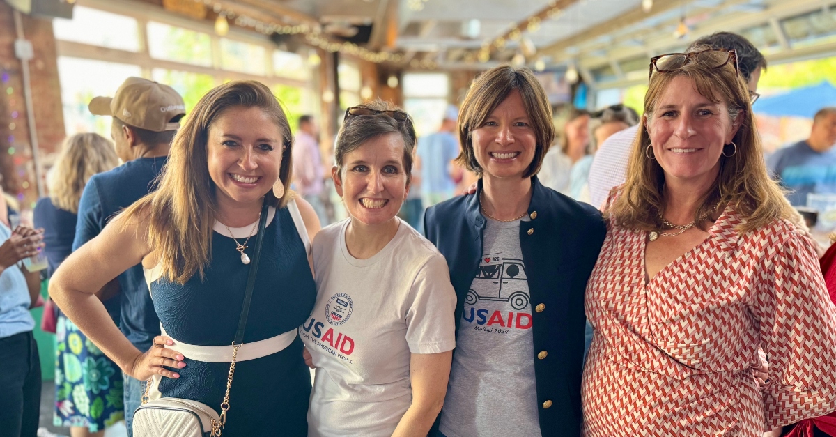 Former USAID employees stand with GlobalGiving employees at a fundraiser