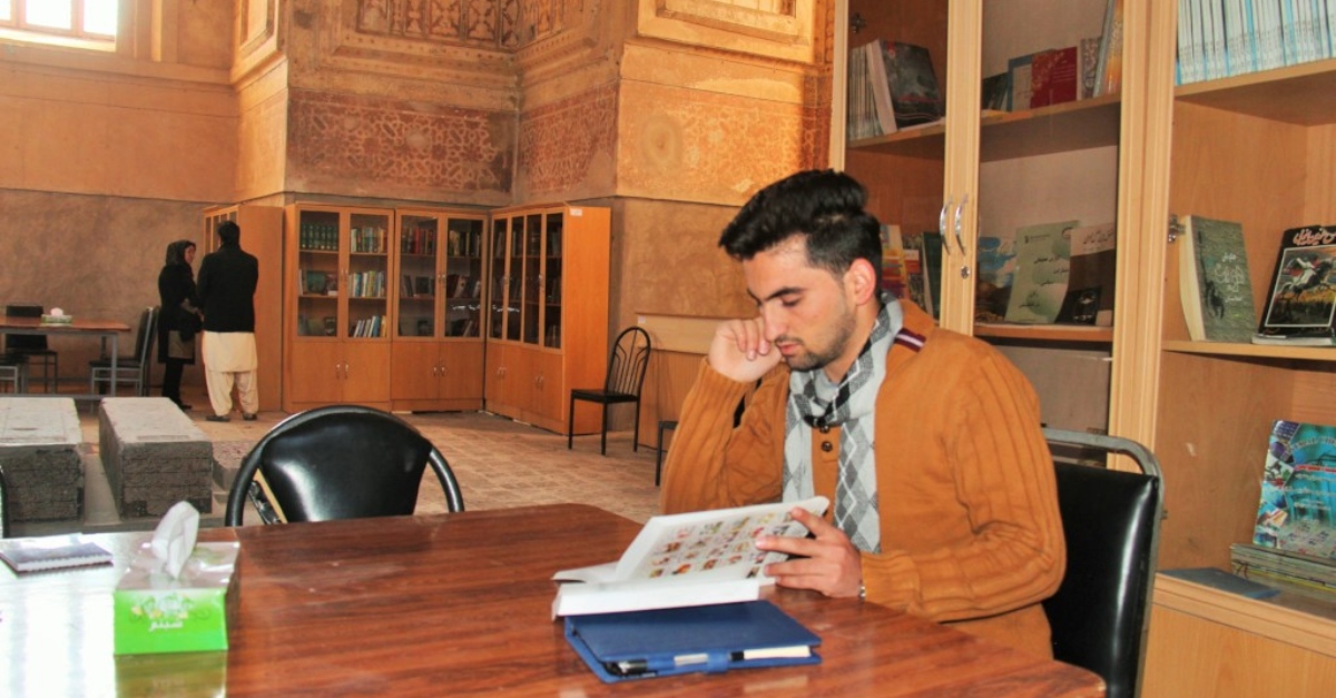 A person looks carefully through a book, sitting in a library
