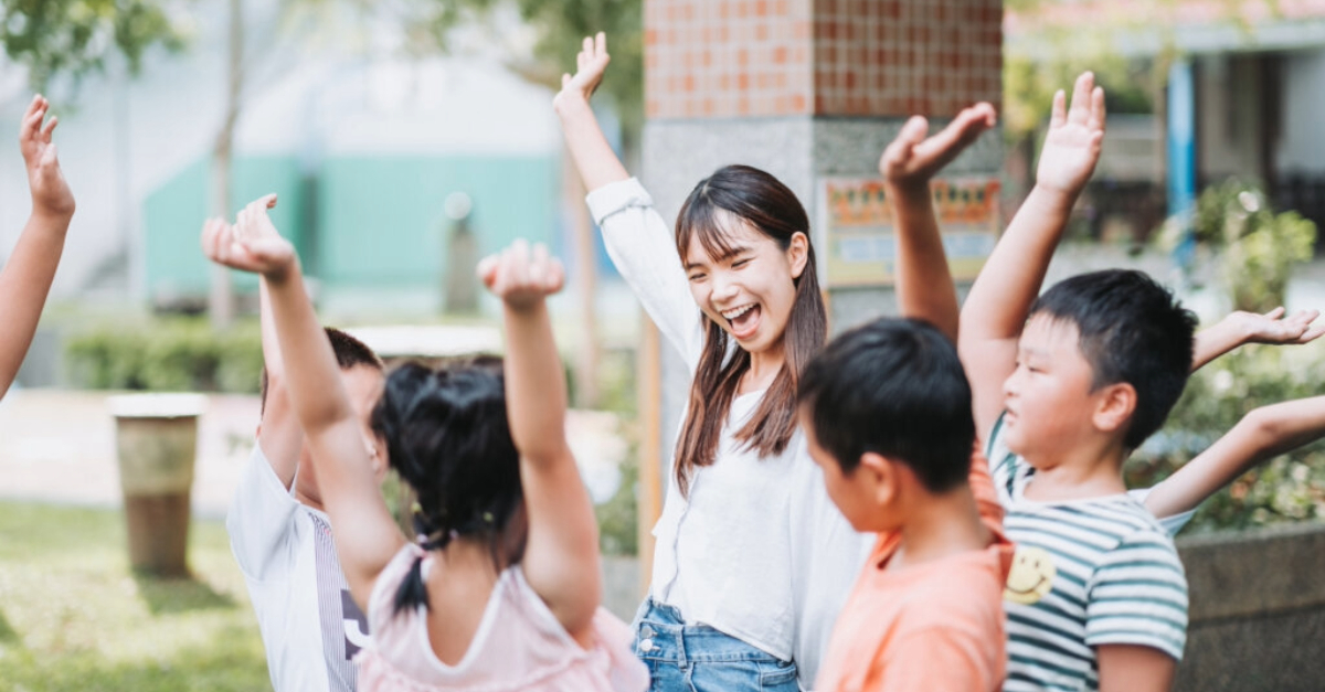 A group of school children raising their hands in celebration.