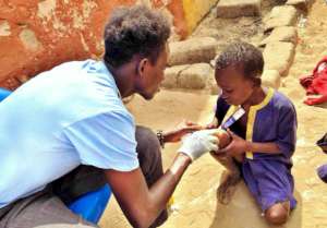 Elhage gently examines a child's sore knee