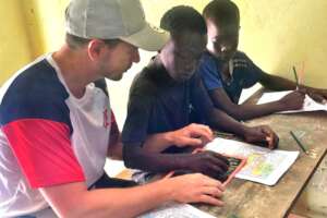 Lucas teaches two talibe children the ABCs