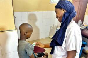 Awa reassures a talibe, taking his temperature
