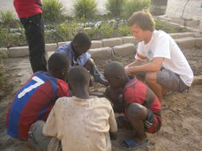 Volunteer helping talibes prepare Nebedaye seeds