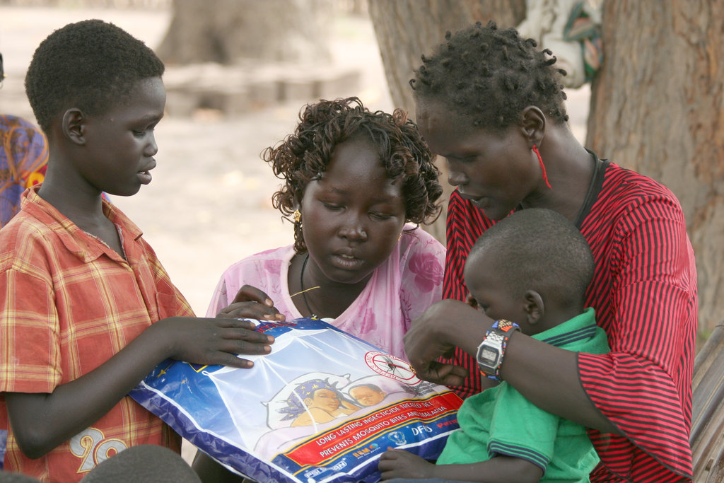Proud mother showing a new bed net to family