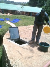 Staff member retrieves water from tank