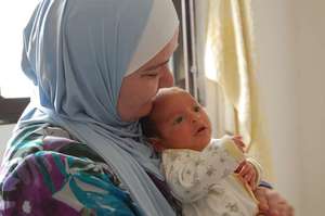 UNHCR's field worker holds a newborn UNHCR/Purvis