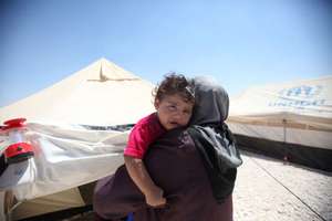 A Syrian mother holds her child in a refugee camp