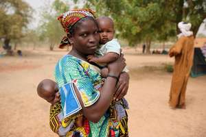 A Malian mother carries children in Burkina Faso