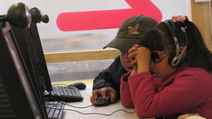 A classmate helps Iris to use the computer