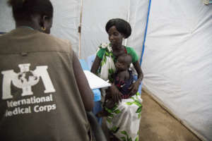 A clinical health worker helps a mother and child