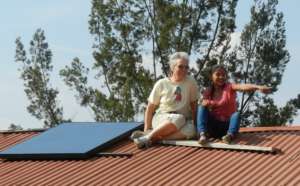 Fatima and volunteer hang out by their 245W panel