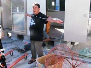 Yutaka Satoh shows octopus trap in front of shed