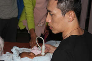 Examining a new born with heart disease.