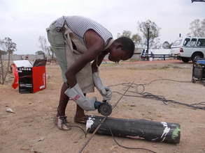 Charity wielding a grinder to cut round bar