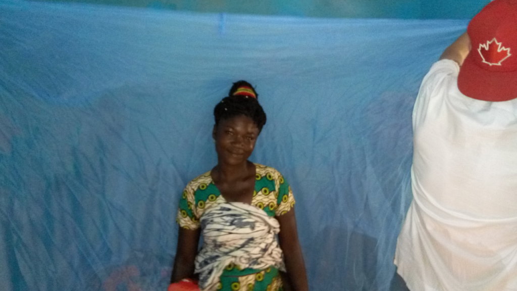 A beneficiary smiles after receiving bed net