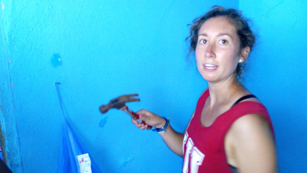 Hannah completes nailing the wall to hang a net.