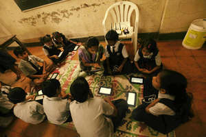 A teacher shows a student how to work on a tablet