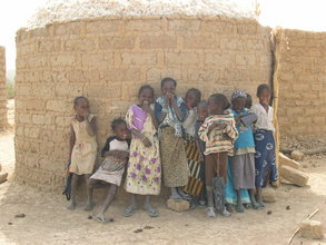 Children standing in front of cotton, stored in a mud-brick cyli