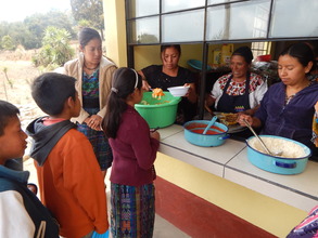 Mothers serve children lunch in new kitchen