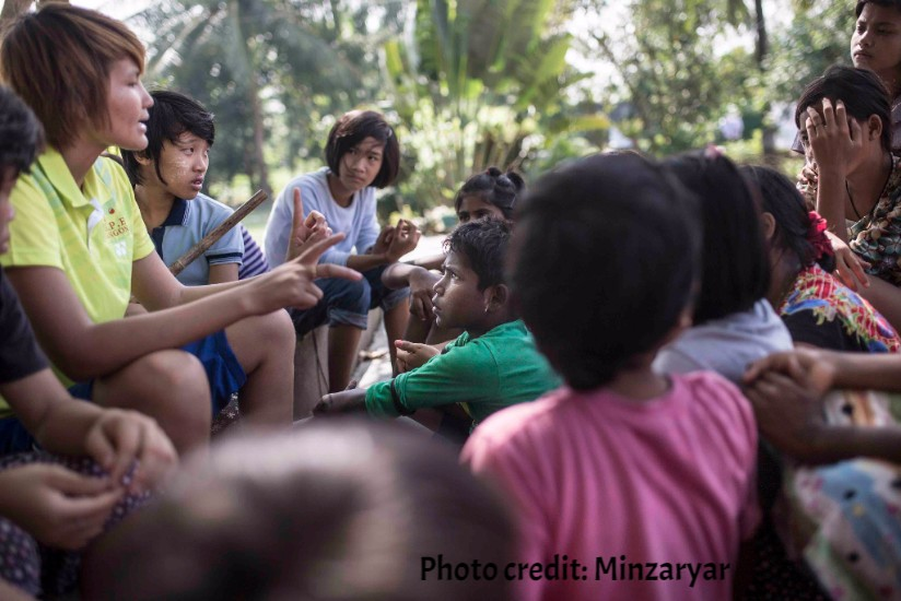 Girls discussing team work under a tree.
