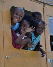 Children waving from a tap-tap bus in Haiti