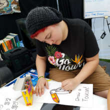 Drawing a toucan at CACE booth at festival